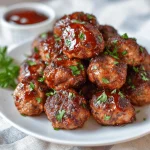 Air fryer meatballs, seasoned and garnished with parsley, in a black air fryer basket.