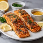 A fork flaking a piece of perfectly cooked air fryer salmon served with roasted asparagus.