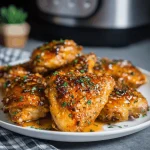 Air fryer honey garlic chicken thighs garnished with cilantro, served on a dark plate.