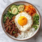 Delicious Korean ground beef bowl with rice, cucumbers, carrots, and green onions.
