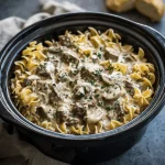 Close-up of a bowl of slow cooker beef stroganoff served over egg noodles.
