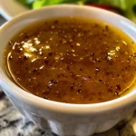 A small bowl brimming with white balsamic vinaigrette, reflecting its fresh ingredients.