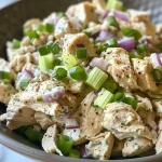 Detailed shot of a chicken salad featuring mayonnaise and garnishes like green onions and lemon.