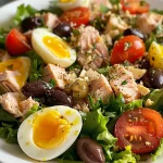 A colorful spread of Niçoise salad showing lettuce, potatoes, and black olives in a bowl.