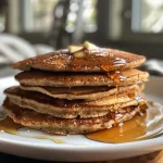 Juicy almond flour pancakes arranged on a wooden table with ingredients nearby.
