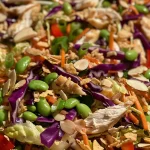 Juicy Asian Chicken Crunch Salad adorned with edamame, almonds, and wonton strips.