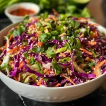 Detailed look at Asian Peanut Slaw garnished with sesame seeds and cilantro leaves.
