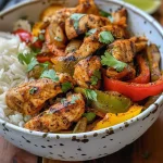 Side view of a Chicken Fajita Bowl overflowing with chicken, peppers, and cilantro.