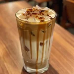 Iced caramel latte filled with ice and topped with whipped cream and caramel sauce.