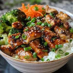 Detailed shot of teriyaki chicken served over rice with fresh vegetables.