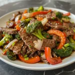 Close-up view of a colorful beef stir fry with broccoli, bell peppers, and carrots.