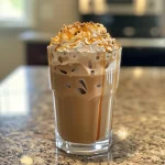 Refreshing caramel iced coffee with a glossy caramel syrup drizzle on top, viewed from the side.