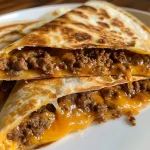 Close-up view of cheesy ground beef quesadillas on a plate.
