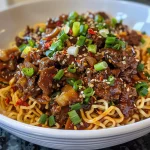 Close-up of Chili Beef Garlic Noodles garnished with green onions.