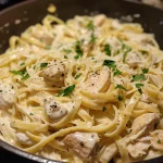 A close-up view of creamy chicken Alfredo pasta with fettuccine, garnished with parsley.