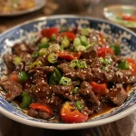 Close-up view of crispy chilli beef with vibrant peppers.