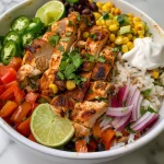 Vibrant chicken burrito bowl showcasing layers of rice, chicken, and fresh garnishes.