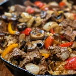 Close-up of a Philly Cheesesteak Skillet with colorful vegetables and melted cheese.