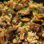 Close-up view of savory beef and mushroom rice pilaf in a bowl.