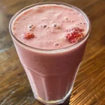 A creamy strawberry vanilla smoothie in a glass, garnished with fresh strawberries.