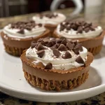 Close-up view of rich chocolate cheesecake cups topped with whipped cream and chocolate shavings.