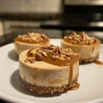 ['A close-up side view of a mini cheesecake topped with caramel drizzle and sea salt.', 'A detailed image of a savory Bariatric salted caramel cheesecake, showcasing its creamy texture.', 'A beautifully presented mini cheesecake with caramel sauce, highlighting its dessert features.', 'An appetizing side view of a protein mini cheesecake with a rich caramel topping and dollops of cream.']