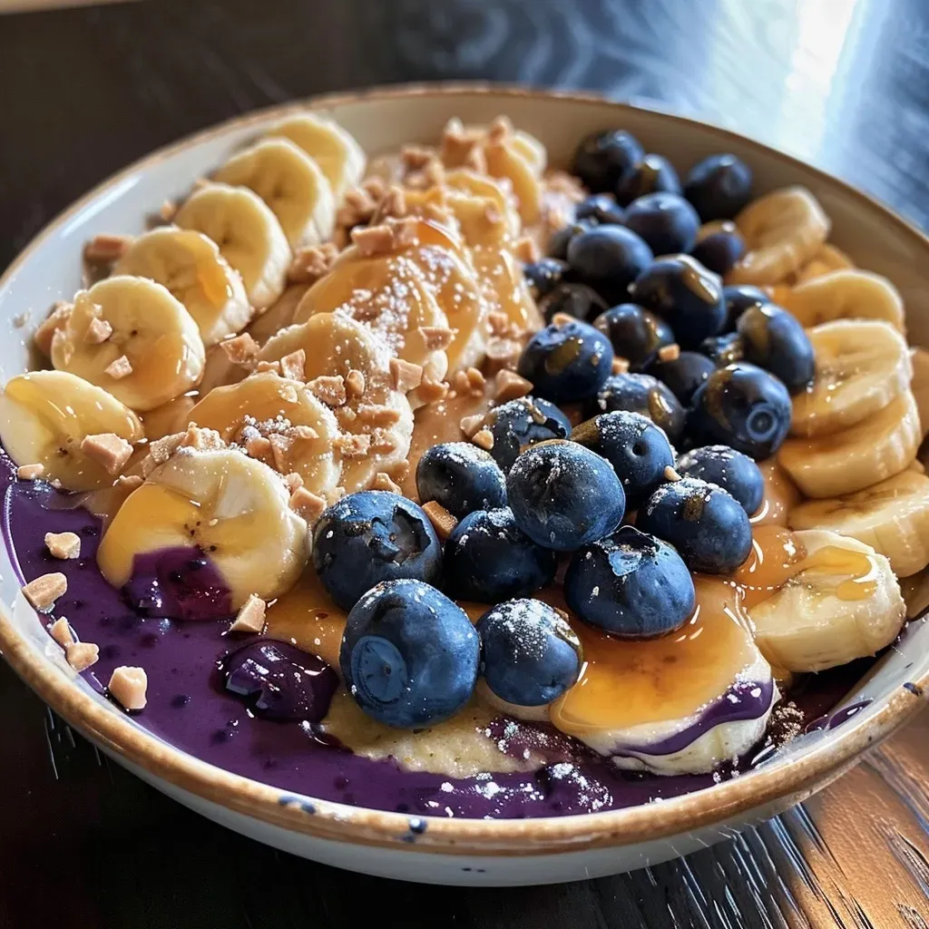 ['Side view of a Blueberry Banana Protein Pancake Bowl topped with fresh blueberries and peanut butter.', 'Close-up of a colorful pancake bowl featuring bananas, blueberries, and creamy peanut butter.', 'Delicious Blueberry Banana Protein Pancake Bowl with a rich texture and vibrant fruit toppings.', 'A hearty stack of protein pancakes adorned with blueberries and a drizzle of maple syrup.']