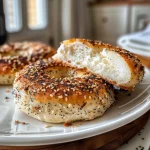 ['Close-up of a golden-brown protein bagel topped with sesame seeds and shredded cheese.', 'Side view of a freshly baked cottage cheese protein bagel with a glossy egg wash and toppings.', 'Juicy protein bagel featuring a fluffy texture and garnished with everything bagel seasoning.', 'An appetizing bagel with a rustic appearance, displaying a tempting cottage cheese filling.']