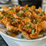 ['Close-up view of crispy chicken wonton cups with green onion garnish.', 'Side view of deliciously filled crispy wonton cups topped with sweet chili sauce.', 'Juicy chicken-filled wonton cups displayed on a plate, showcasing their golden crispiness.', 'Appetizing close-up of chicken wonton cups with vibrant green onions and a dipping sauce.']