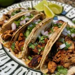['Close-up view of juicy chicken street tacos topped with onions and cilantro.', 'Side view of delicious chicken tacos garnished with lime wedges and cotija cheese.', 'Colorful presentation of chicken street tacos with fresh ingredients and vibrant toppings.', 'Tasty chicken tacos served on a plate with lime, cilantro, and salsa verde.']