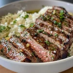 ['Close-up view of a Garlic Butter Steak and Rice Bowl with glistening steak slices on a bed of rice.', 'Side view of a bowl featuring Garlic Butter Steak, cooked rice, and garnished with parsley.', 'Juicy steak pieces resting atop white rice with melted garlic butter, captured in vivid detail.', 'Deliciously plated Garlic Butter Steak and Rice Bowl showcasing tender steak and fluffy rice.']