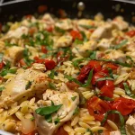 ['Close-up view of One Pot Marry Me Chicken Orzo with chicken pieces and herbs.', 'Juicy chicken and orzo dish garnished with fresh basil and sun-dried tomatoes.', 'A delicious bowl of orzo and chicken in creamy sauce, topped with Parmesan.', 'Side view of a vibrant One Pot Marry Me Chicken Orzo, showcasing ingredients and texture.']