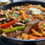 ['Close-up view of a vibrant steak fajita rice skillet with colorful vegetables.', 'Juicy steak and bell peppers mixed with rice in a skillet, showcasing a hearty meal.', 'A delicious steak fajita rice dish, featuring sliced sirloin, peppers, and cheese.', 'Side view of a sizzling steak fajita rice skillet, highlighting fresh ingredients and textures.']