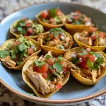 ['Close-up view of Taco Cups filled with ground beef and cheese.', 'Juicy Taco Cups displayed on a surface, showcasing toppings and textures.', 'Side shot of mini flour tortilla cups filled with colorful taco ingredients.', 'Delicious Taco Cups featuring diced tomatoes, onions, and guacamole.']