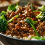 ['Juicy high protein ground beef bowl topped with honey and sriracha, broccoli, and jasmine rice.', 'Close-up of a hot honey bowl with ground beef, garnished with broccoli and served over rice.', 'Colorful bowl featuring ground beef drizzled with honey, broccoli, and jasmine rice from a side view.', 'Side view of a hearty ground beef bowl with fresh broccoli, rice, and a spicy honey sauce.']