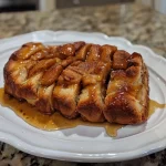 ['A close-up side view of a loaf of apple butter pull-apart bread, showcasing its golden-brown crust and soft, fluffy texture.', 'Delicious apple butter pull-apart bread with a warm, inviting appearance, highlighting its gooey layers and rich color.', 'A tempting side view of apple butter pull-apart bread, revealing its luscious, buttery strands and appealing golden crust.', 'Close-up of a sliced apple butter pull-apart bread, displaying its moist interior and the rich, warm hues of apple butter.']