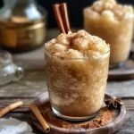 ['Close-up view of a refreshing Apple Cider Slushie in a glass with ice and spices.', 'Side view of a frosty Apple Cider Slushie, showcasing its vibrant color and ice texture.', 'Glass filled with an icy Apple Cider Slushie, garnished with a cinnamon stick.', 'Appetizing Apple Cider Slushie with frost on the glass and a hint of spices visible.']