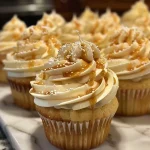 ['A close-up side view of decadent caramel macchiato cupcakes topped with caramel drizzle and coffee cream.', 'A detailed view of sumptuous caramel macchiato cupcakes showcasing creamy frosting and a caramel swirl.', 'A side-angle shot of rich caramel macchiato cupcakes garnished with a glossy caramel topping.', 'Close-up of moist caramel macchiato cupcakes with a luscious frosting and caramel sauce decoration.']