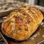 ['Close-up view of a crusty No Knead Rosemary Bread loaf with a golden-brown crust.', 'Side view of freshly baked No Knead Rosemary Bread showcasing herbs and texture.', 'Detailed shot of No Knead Rosemary Bread with visible rosemary leaves and crispy crust.', 'Juicy, inviting No Knead Rosemary Bread loaf with a rustic appearance and warm hues.']