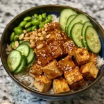 ['A close-up view of delicious peanut tofu bowls featuring vibrant ingredients.', 'Side view of a colorful peanut tofu bowl with tofu cubes, edamame, and cucumbers.', 'Juicy peanut tofu bowl filled with rice, vegetables, and garnished with sesame seeds.', 'Detailed shot of a peanut tofu bowl showcasing tofu, rice, and fresh toppings.']