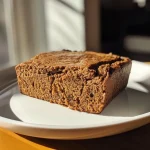 ['Close-up view of a moist Protein Gingerbread Loaf with spices visible.', 'Side view of Protein Gingerbread Loaf showcasing its texture and rich color.', 'Juicy Protein Gingerbread Loaf with a golden-brown crust and detailed ingredients scattered around.', 'Sliced Protein Gingerbread Loaf revealing a fluffy interior, accented by spices.']