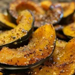 ['Close-up view of roasted acorn squash halves drizzled with maple syrup.', 'Side view of juicy roasted acorn squash with a golden-brown glaze.', 'Close-up of a roasted acorn squash, highlighting its caramelized edges.', 'Appetizing roasted acorn squash garnished with a sprinkle of sea salt.']
