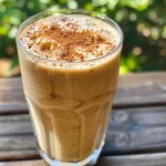 ['Close-up side view of a Vanilla Chai Protein Shake in a glass with ice.', 'A refreshing Vanilla Chai Protein Shake featuring spices, garnished with a sprinkle of nutmeg.', 'Side view of a creamy Vanilla Chai Protein Shake in an attractive glass with ice cubes.', 'Delicious Vanilla Chai Protein Shake in a glass, showcasing its rich, creamy texture.']