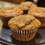 Close-up view of a chai spice pumpkin muffin with a golden-brown top.