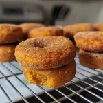 Close-up view of golden-brown mini pumpkin donut muffins coated in cinnamon sugar.