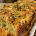 Close-up view of Savory Herb Stuffing Bread showcasing a golden crust and herbs.