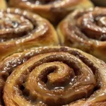 Close-up view of soft gingerbread cinnamon rolls drizzled with icing.